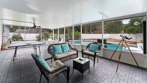 A covered patio with wicker furniture, a pool, and a telescope. - Putt Putt Pool Home - Mini Golf,Grill,Ping Pong (Jacksonville)