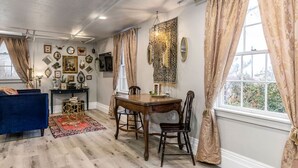 A dining area with a wooden table and chairs, a blue sofa, and a patterned rug.