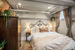 Une chambre à coucher avec un lit, des lampes de chevet, une armoire et une fenêtre avec des rideaux.