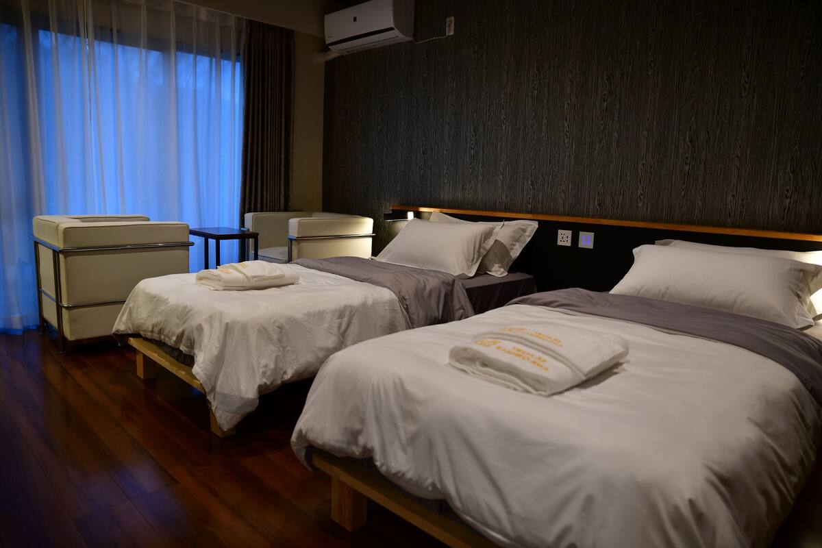 A hotel room with two beds, a desk, and a chair.
