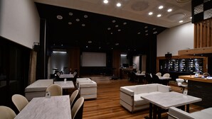 A modern restaurant with wooden flooring, white tables and chairs, and a stage for live performances. - Villa 33 Kashikojima (Shima)
