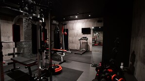 A gym with various exercise equipment, including a bench press, squat rack, and weight plates. - Villa 33 Kashikojima (Shima)