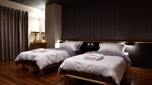 A modern hotel room with two beds, wooden flooring, and a dark accent wall. - Villa 33 Kashikojima (Shima)