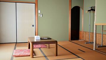 Una habitación japonesa tradicional con suelo de tatami, una mesa de madera baja, un cojín rosa y una puerta corredera.