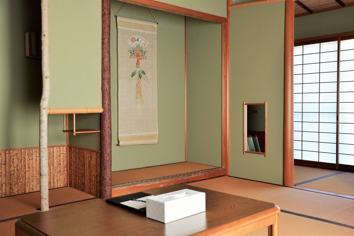 A traditional Japanese room with tatami flooring, a low wooden table, a hanging scroll, and a shoji screen door.