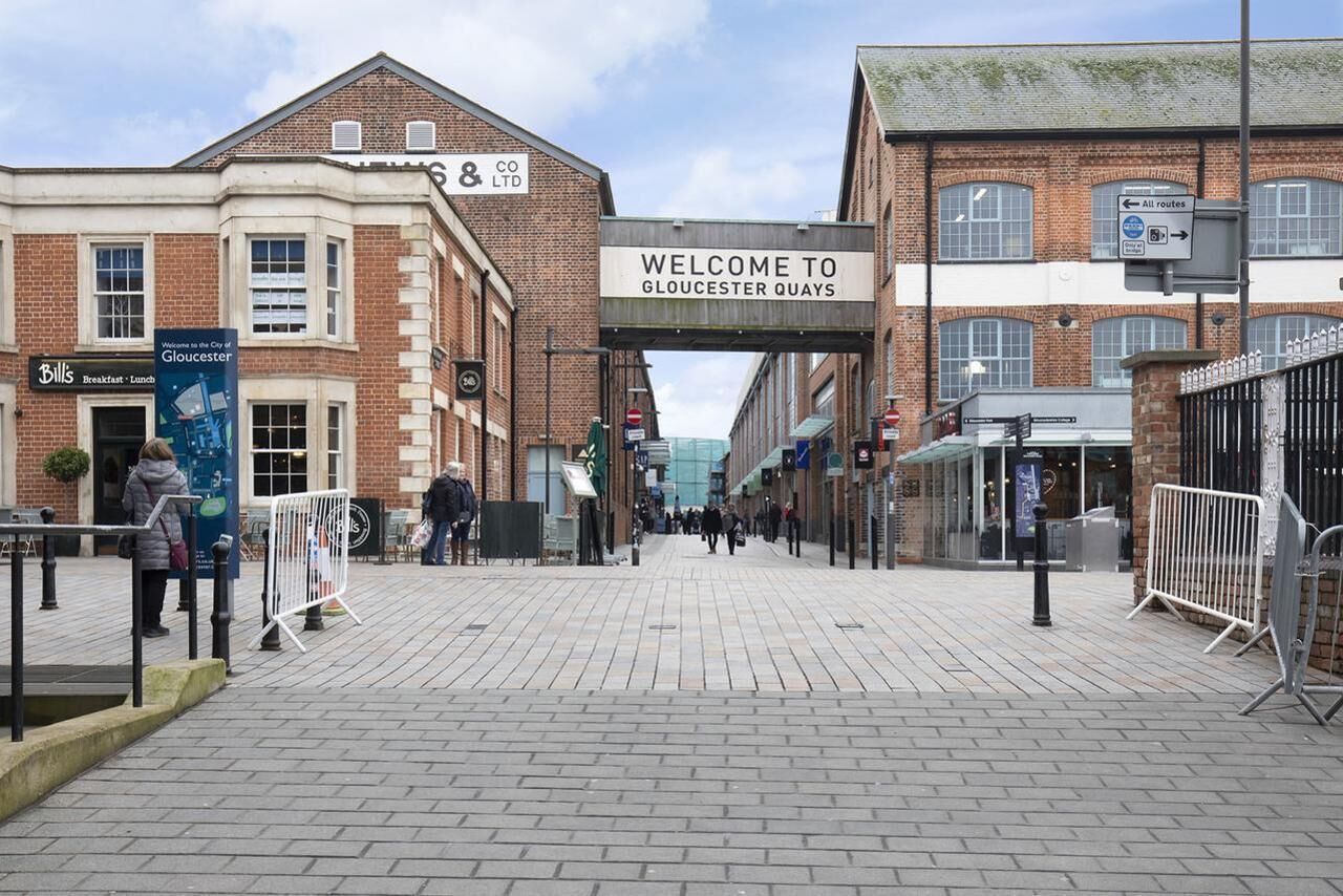 A brick building with a sign reading "Welcome to Gloucester Quays" and a sign for "8 & Co Ltd".