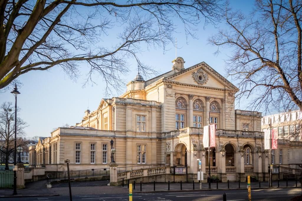 Un bâtiment historique à l’architecture classique, caractérisé par une entrée imposante et des fenêtres disposées de manière symétrique.