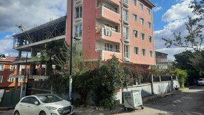 En byggnad med flera våningar, en rosa fasad, balkonger och en byggarbetsplats på de övre våningarna.