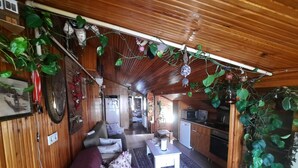 Ett mysigt vardagsrum med trägolv, en soffa, ett litet bord och ett kök i bakgrunden.