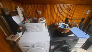 A laundry area with a washing machine and dryer, a basket with cleaning supplies, and a wicker basket with a towel.