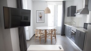 A modern kitchen with a dining area, a flat-screen TV, and a sofa. - Flats Friends Soho Suites 1 bedroom (Valencia)