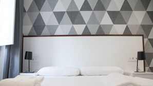 A neatly made bed with white linens, two bedside lamps, and a geometric patterned wall. - Flats Friends Soho Suites 1 bedroom (Valencia)