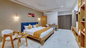 Habitación de hotel con cama, escritorio, silla y una pequeña mesa con frutas.