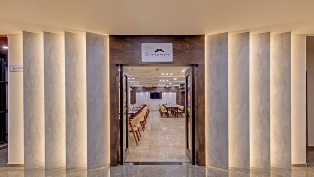 Un amplio vestíbulo de hotel con columnas de mármol, un mostrador de recepción alargado y un letrero que indica la ubicación como "Cinnamon".