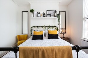 A bedroom with a bed, a nightstand, a lamp, and a window.