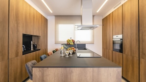 A modern kitchen with wooden cabinetry, a central island, and a built-in oven.