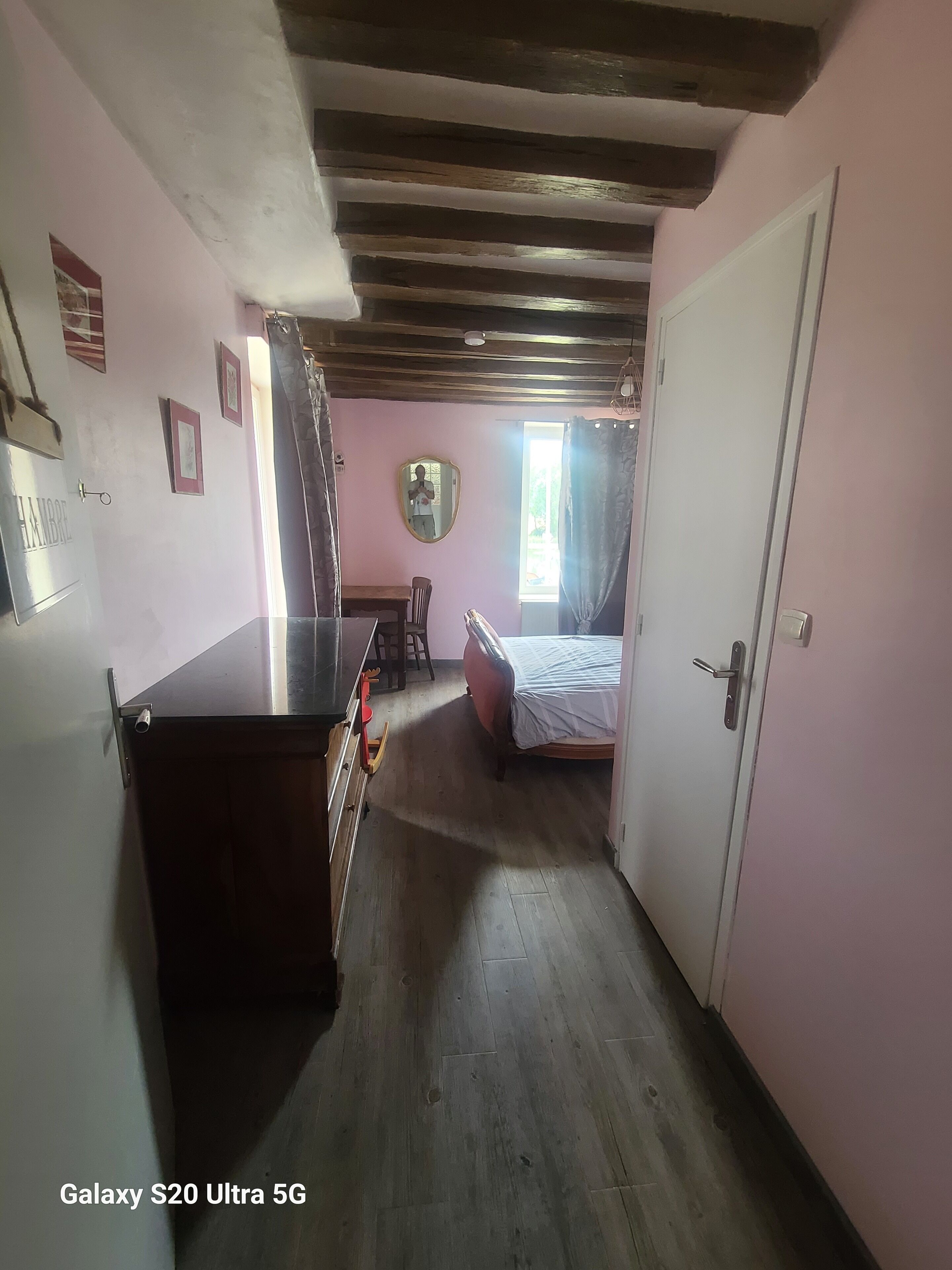 Un pasillo estrecho con una cama, una mesita y un espejo en la pared.