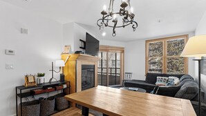 Un salon moderne avec une table à manger en bois, un canapé, une cheminée et un téléviseur.