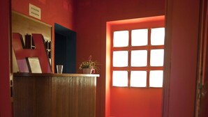 A hallway with a wooden floor, a reception desk, and a window with multiple panes. - Diana (Lucca)