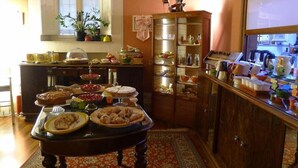 A kitchen with a dining table set with various dishes, a cabinet with glass doors, and a window with plants. - Diana (Lucca)