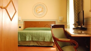 A hotel room with a bed, a chair, a television, and a decorative wall piece. - Diana (Lucca)