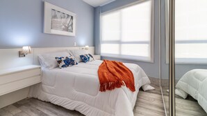 A bedroom with a bed, a nightstand, a wall-mounted lamp, a window with blinds, and a framed picture on the wall. - Av0203 Studio Avanhandava (São Paulo)