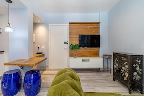 Uma sala de estar moderna com uma mesa de jantar de madeira, um sofá verde e um aparador decorativo com motivos florais.