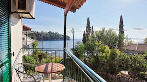 Ein Balkon mit Tisch und Stühlen, der auf ein Gewässer und eine hügelige Landschaft blickt.