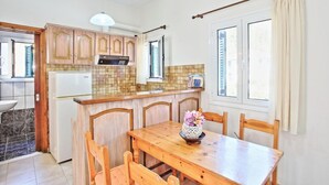 Eine Küche mit Holzausstattung, einem weißen Kühlschrank, einem Esstisch mit Stühlen und einem Fenster mit Vorhängen.