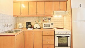 Una cocina con armarios de madera, microondas, tostadora, hervidor, cafetera, fregadero y estufa.
