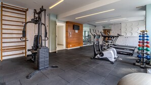 Ett gym med träningsutrustning, en vägg av trä och en spegel.