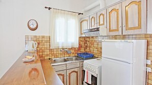 A compact kitchen with a wooden countertop, a sink, a stove, and a refrigerator. - Zoulis Andonis in Kalami (Corfu)