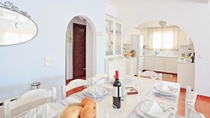 Un coin repas avec une table dressée pour quatre personnes, une bouteille de vin et du pain sur la table.