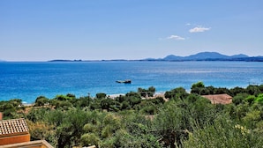 A coastal view with a clear blue sea, a small dock, and a mountainous backdrop. - Casa do Tina in Mparmpati (Corfu)