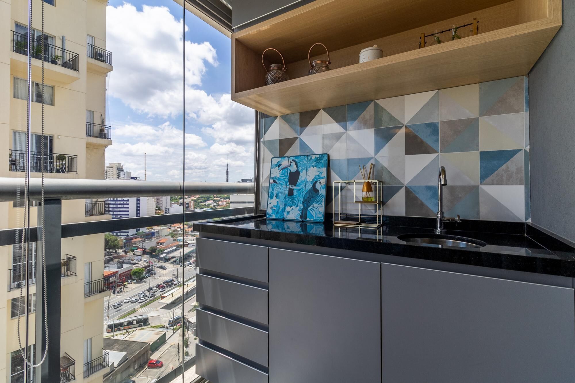 Cozinha moderna com bancada preta, pia e painel de azulejos com padrões geométricos.