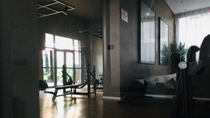 A gym with exercise equipment, large windows, and a sofa.