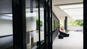 A modern building with large windows and a covered outdoor seating area with black chairs and tables.