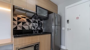A compact kitchen with a built-in microwave, stainless steel refrigerator, and a gas stove.