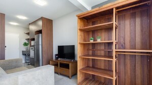 A modern living room with a wooden entertainment unit, a flat-screen TV, and a dining area with a refrigerator. - Ycp1903 in S o Paulo (São Paulo)