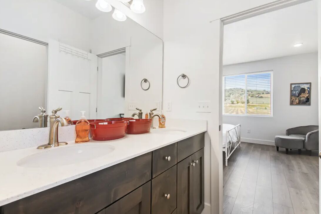 A modern bathroom with a large mirror, dual sinks, and a vanity with dark cabinets.