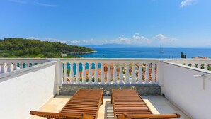A balcony with two wooden lounge chairs, a white balustrade, and a view of the sea with boats and a sailboat. - Faros Dio Gaios Studio sea Views Private Sun-loungers (Paxos)