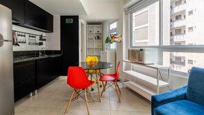 A compact living space with a kitchen, dining area, and seating by a window. - Av0606 Studio Avanhandava (São Paulo)