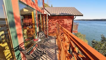 Une terrasse en bois, agréée de mobilier d’extérieur, donnant sur un lac.