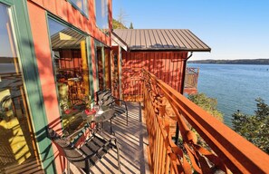 A wooden deck with outdoor furniture overlooking a lake.
