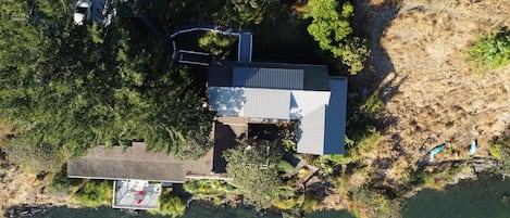 An aerial view of a property with a main building, a smaller structure, and a dock.