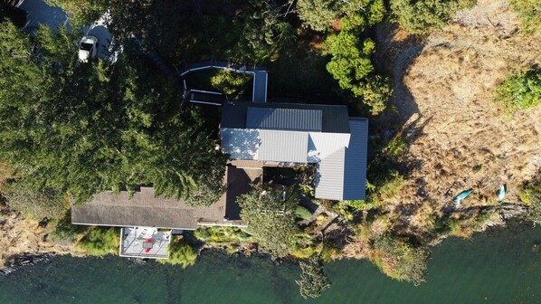 An aerial view of a property with a main building, a smaller structure, and a dock.
