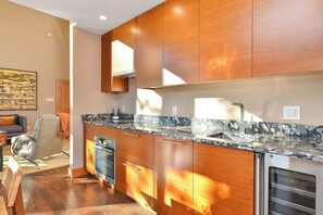 A modern kitchen with wooden cabinets, a marble countertop, and built-in appliances.