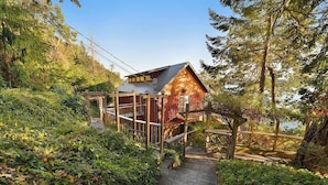 Eine Holzhütte mit Blechdach, umgeben von dichtem Grün und einer Holzterrasse.