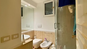 Une salle de bain moderne équipée d’une douche, de toilettes, d’un bidet et d’un lavabo.