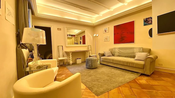 Un salon bien éclairé, avec un canapé, un fauteuil et un grand miroir.